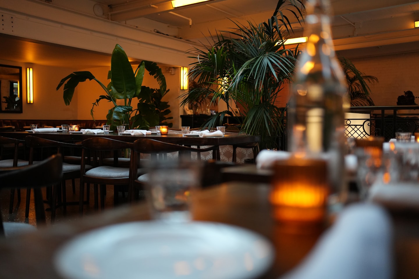 Holztische mit Gedecken und Kerzen in einem gemütlichen Restaurant.